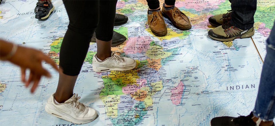 Young migrants standing on a world map