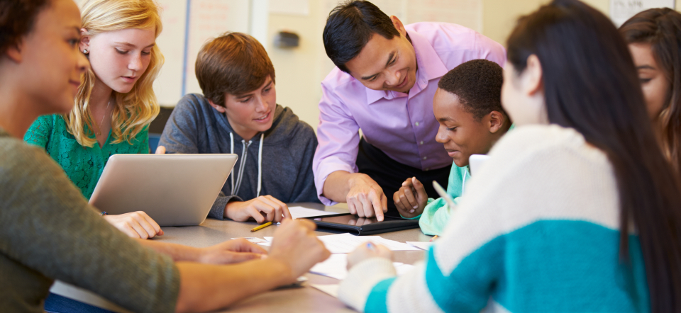 Diverse students and a teacher at a table studying. 